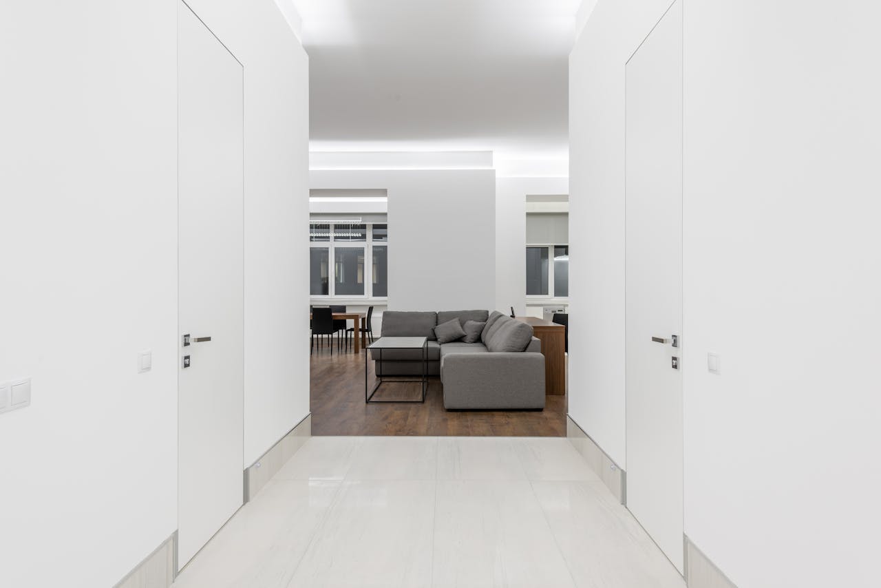 Spacious minimalist living room with gray sofa and white walls.