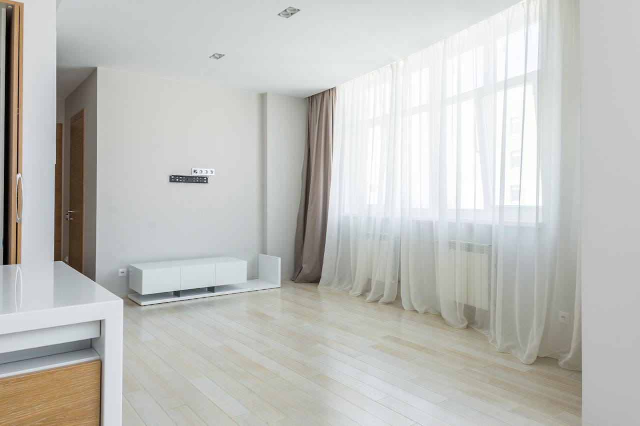 Bright modern minimalist apartment interior with large windows and sheer curtains.